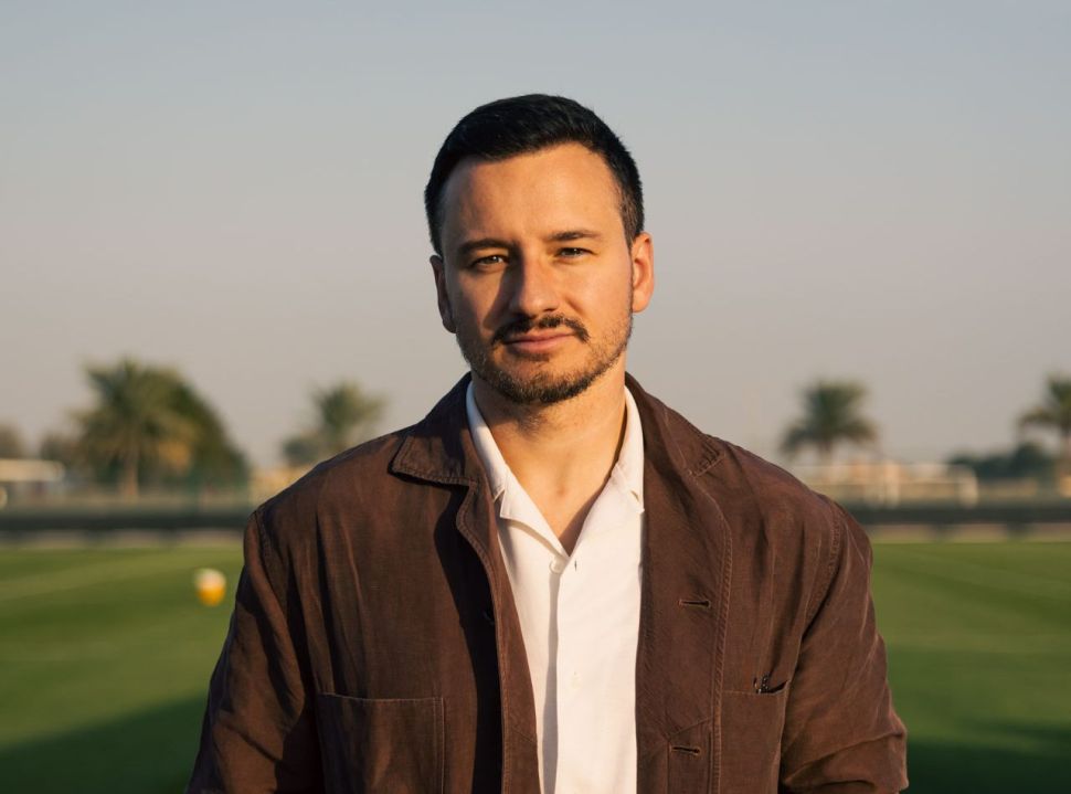 RJ Phillips waring a white shirt and a brown jacket