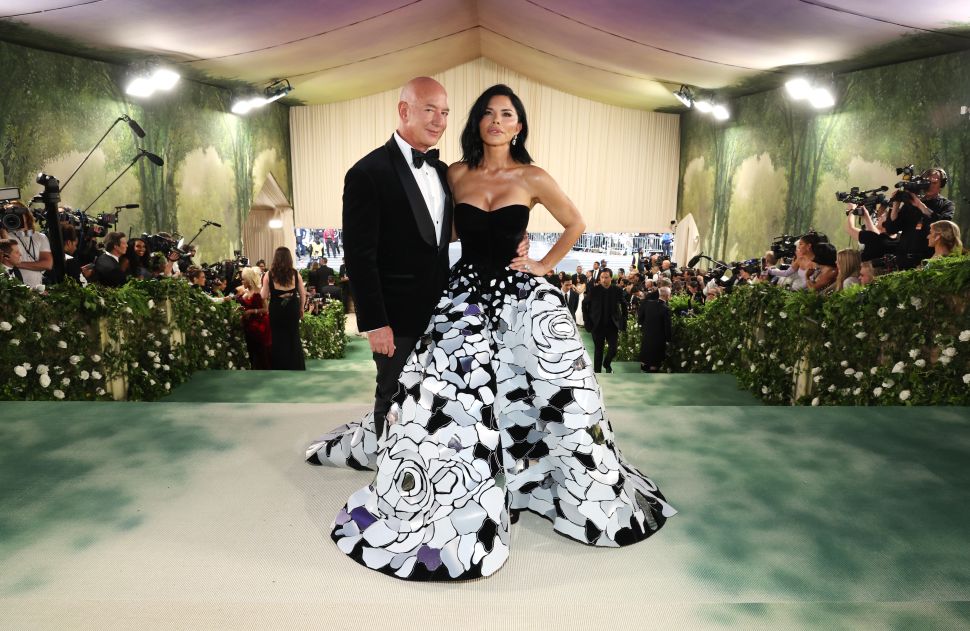Man in suit and woman in black and white dress pose atop green stairs