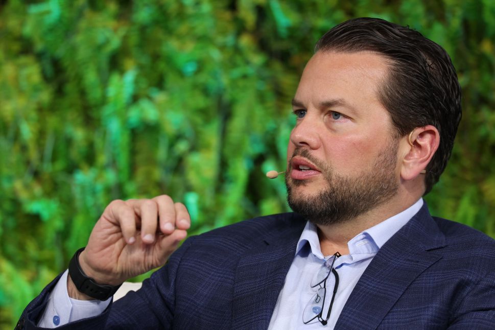 Image of man in suit sitting onstage in chair