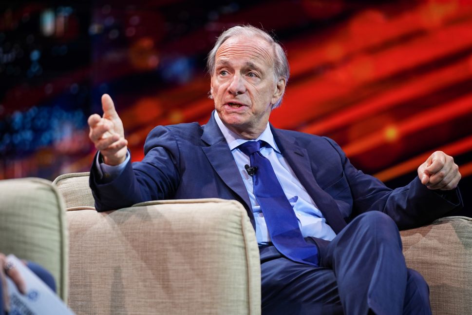 Man in navy suit sits in chair onstage