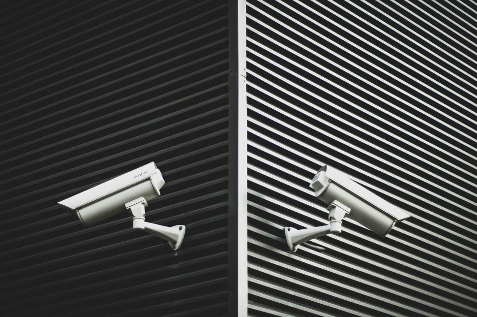 Two security cameras mounted against a building point in opposite directions