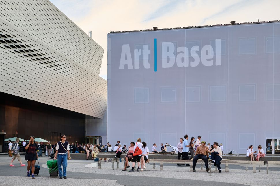 People mill about in front of a large building reading Art Basel